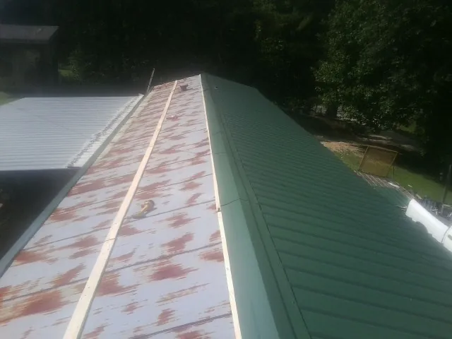 Old rusted panels beside newly installed green metal roofing — Wind Damage Roof Repair by Roofing Brothers in Elkton