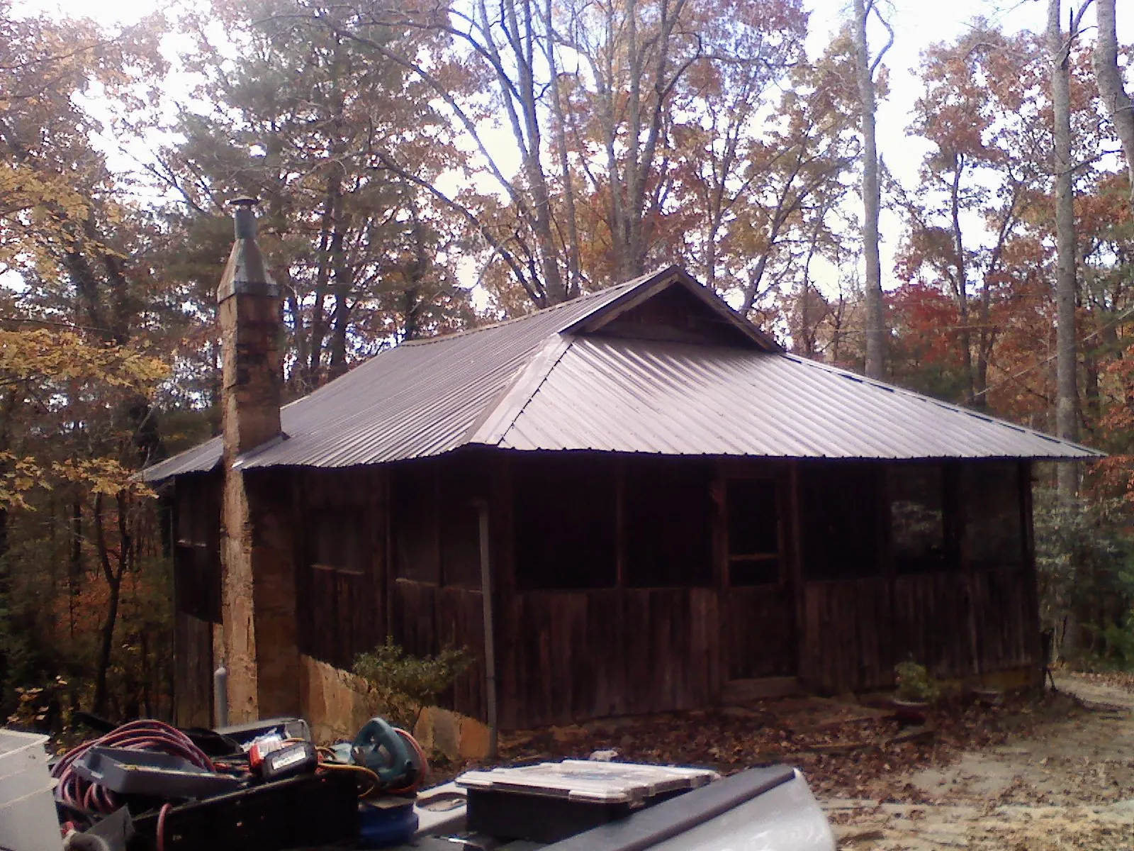 Brown metal hip roof on an old cabin with a stone chimney in Elkton